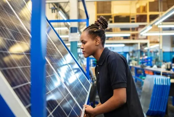 Side view of a female employee inspecting newly manufactured solar panels in company. Woman quality engineer examining solar panels in factory.